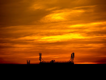 Silhouette of crane against dramatic sky during sunset