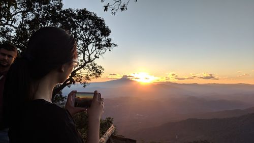 Woman photographing at sunset