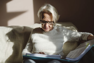 Senior woman with short white hair reading documents at home