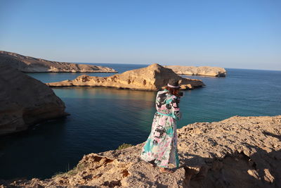 Woman standing at sea against clear sky