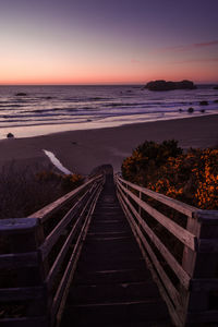 Scenic view steps by sea against sky during sunset