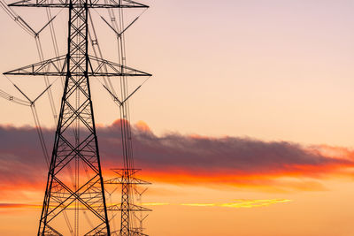 Low angle view of silhouette electricity pylon against sky during sunset