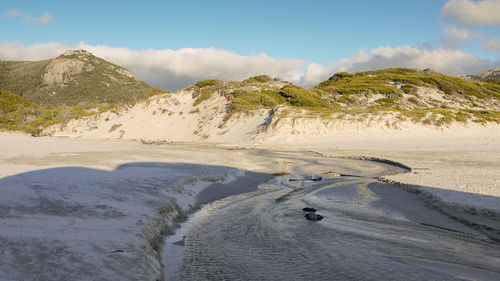 Scenic view of sand dunes against sky