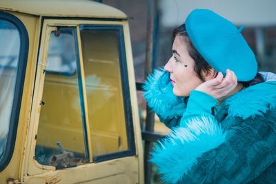 Young woman looking at reflection in glass of land vehicle