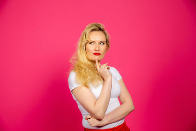 Portrait of woman standing against pink background