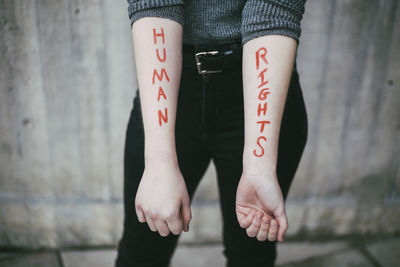 Midsection of female protestor showing equal rights written on hand