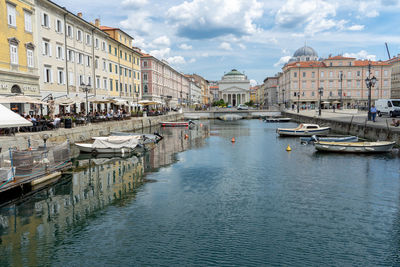 Sailboats moored in canal amidst buildings in city against sky