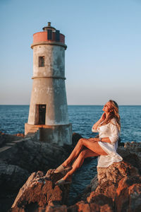 Lighthouse by sea against sky