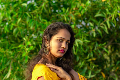 Portrait of beautiful young woman against plants