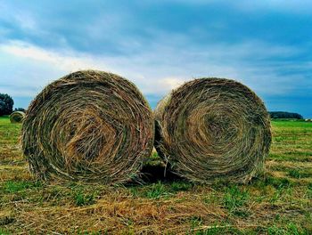 Close-up of hay bales on field against sky