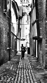 Full length rear view of woman walking in alley