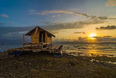 Lifeguard hut on beach against sky during sunset