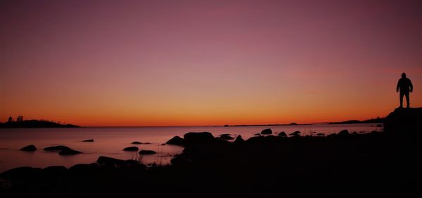 Silhouette people on beach against sky during sunset