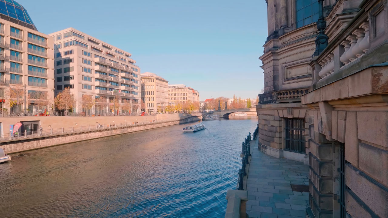 RIVER AMIDST BUILDINGS IN CITY AGAINST SKY