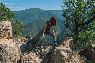 Full length of woman standing on rocks against mountain