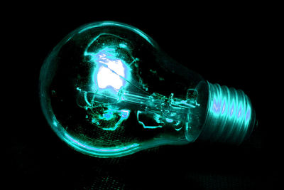 Close-up of illuminated light bulb against black background