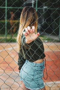 Heeden portrait of young woman through chainlink fence