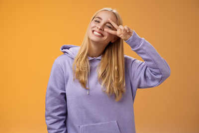 Young woman standing against yellow background