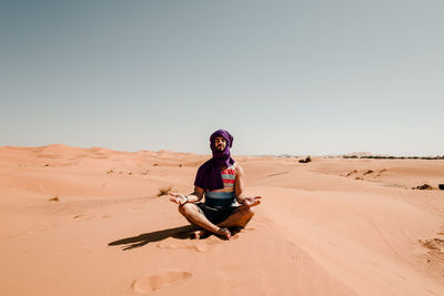 A man in a turban meditating on a dune in the sahara desert