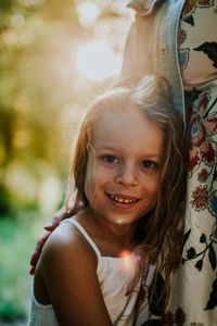 Vertical portrait of young girl hugging mother and smiling