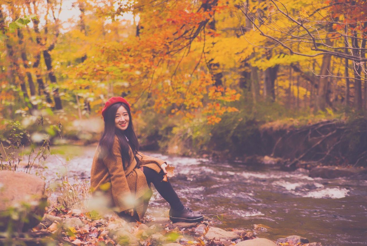 autumn, young adult, real people, tree, young women, one person, leisure activity, lifestyles, plant, forest, nature, land, smiling, portrait, looking at camera, sitting, change, women, day, beauty in nature, outdoors, beautiful woman, hairstyle, warm clothing