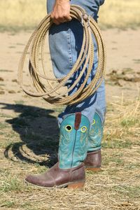 Low section of man holding rope while standing on land