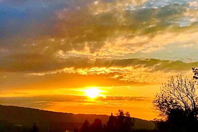 Scenic view of dramatic sky over silhouette landscape during sunset