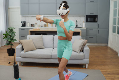 Full length of woman sitting on sofa at home