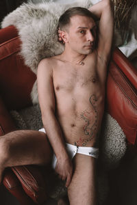 Midsection of shirtless man lying on bed at home