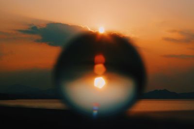 Close-up of crystal ball against sky during sunset