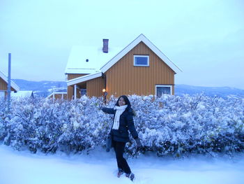 Full length of woman standing on snow covered house