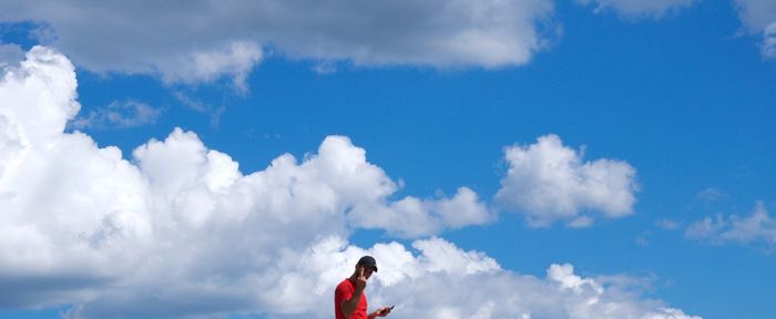 Low angle view of person against cloudy sky