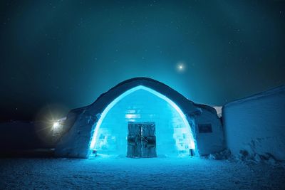 Illuminated ice hole against sky at night