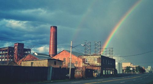 Rainbow over road against cloudy sky