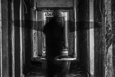 Rear view of silhouette man standing in abandoned building