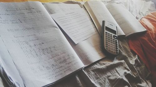 High angle view of books with calculator on bed