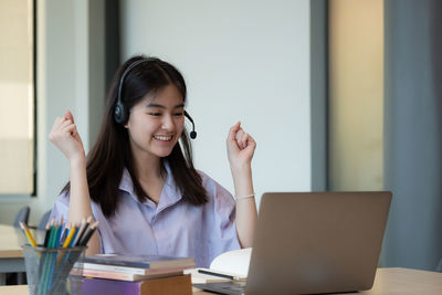 Young woman using phone while sitting on table