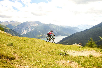 Man riding bicycle on mountain against sky