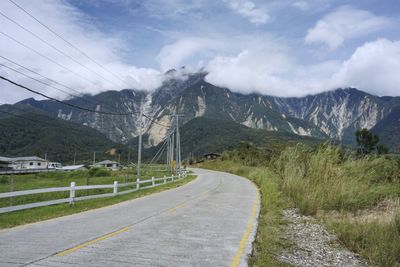 Road by mountains against sky