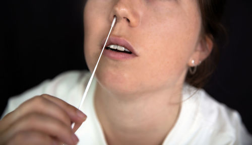 Woman taking covid test against black background