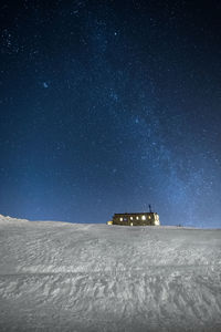 Built structure on snow covered land against sky at night