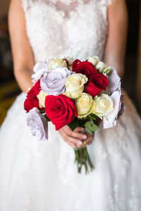 Midsection of bride holding rose bouquet in wedding ceremony