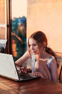 Girl using laptop while sitting on table