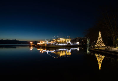 Illuminated bridge over lake against clear sky at night