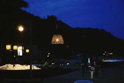 Illuminated street lights against sky at night