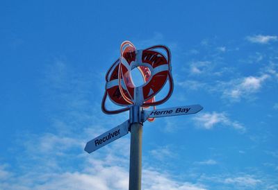 Low angle view of road sign against blue sky