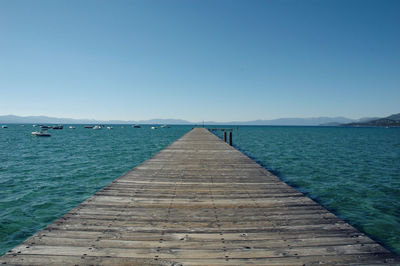 Pier on sea against blue sky