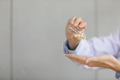 Close-up of hand holding glass against wall