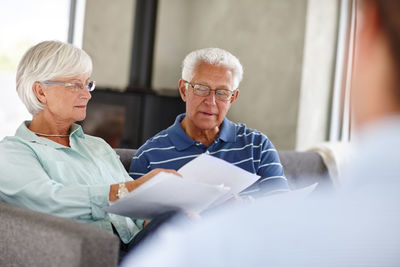 Senior man and woman with documents sitting at home
