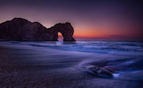 Scenic view of rocks in sea against sky during sunset